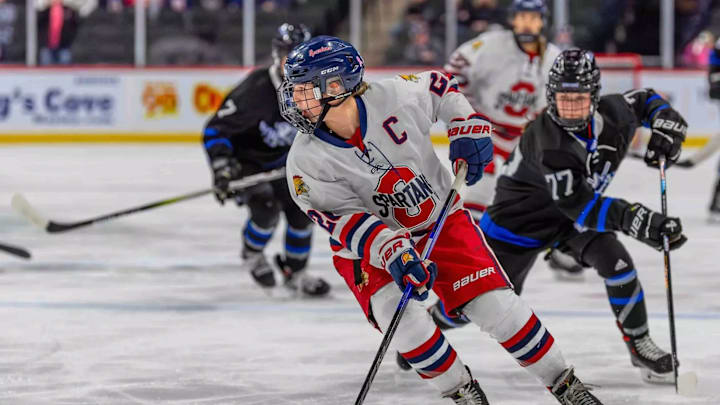 Grace Bickett handles the puck in a high school hockey game for Orono High School.