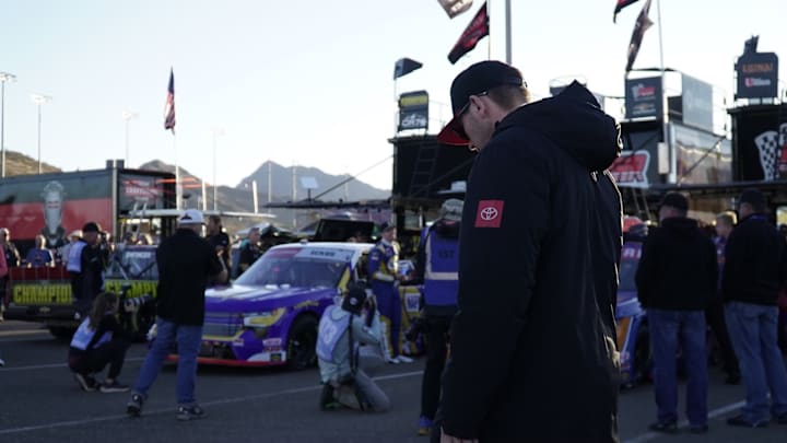 Taylor Gray (pictured in the Toyota jacket), looks in the direction of Christian Eckes and the No. 19 McAnally-Hilgemann Racing Chevrolet in the Phoenix Raceway garage area, one week after their dustup at Martinsville.