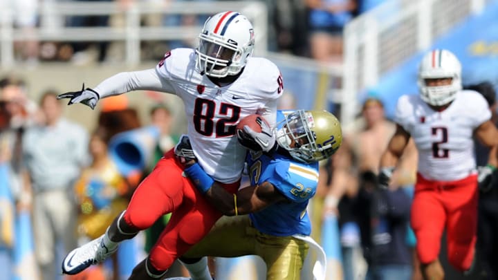 Oct 30, 2010; Pasadena, CA, USA; Arizona Wildcats wide receiver Juron Criner (82) gets tacked by UCLA Bruins corner back Andrew Abott during the game at the Rose Bowl.  Mandatory Credit: Kelvin Kuo-Imagn Images