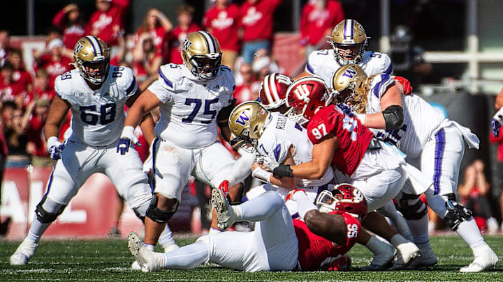 The UW offensive line watches as Indiana's Mario Landino (97) sacks Washington's Will Rogers (7).