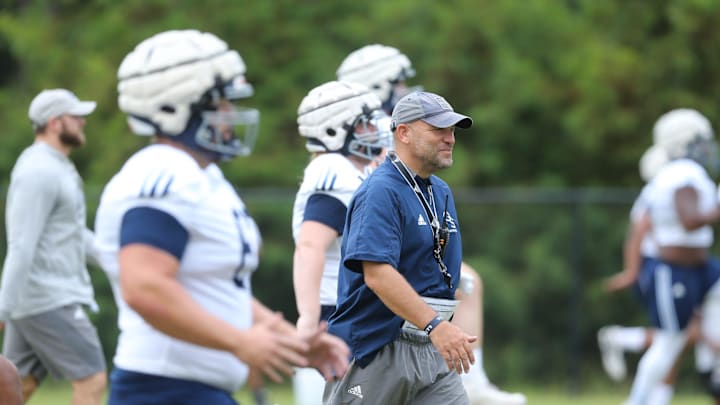 Georgia Southern coach Chad Lunsford walks through as the team warms up before practice.