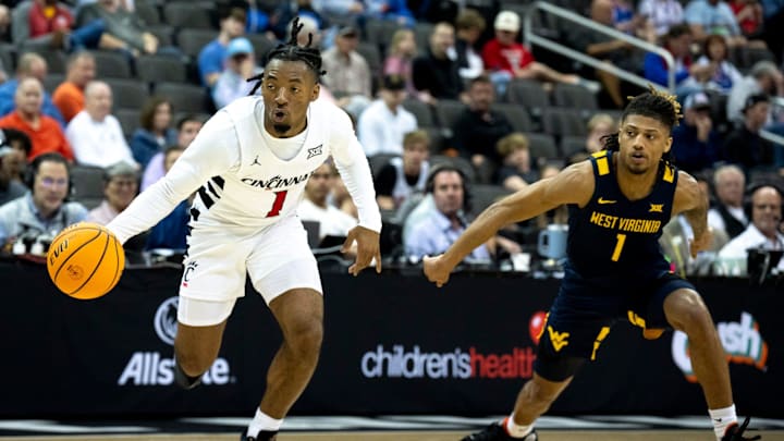 Cincinnati Bearcats guard Day Day Thomas (1) handles the ball as West Virginia Mountaineers guard Noah Farrakhan (1) defends in the first half of the Big 12 Conference tournament between Cincinnati Bearcats and West Virginia Mountaineers at T-Mobile Center in Kansas City, Mo., on Tuesday, March 12, 2024.