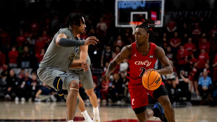 Cincinnati Bearcats guard Jizzle James (2) drives on West Virginia Mountaineers guard RaeQuan Battle (21) in the second half of the NCAA basketball game between Cincinnati Bearcats and West Virginia Mountaineers at Fifth Third Arena in Cincinnati on Saturday, March 9, 2024. Cincinnati Bearcats guard Jizzle James (2) drives on West Virginia Mountaineers guard RaeQuan Battle (21) in the second half of the NCAA basketball game between Cincinnati Bearcats and West Virginia Mountaineers at Fifth Third Arena in Cincinnati on Saturday, March 9, 2024.