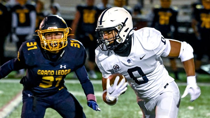 East Lansing's Jace Clarizio, right, runs for a gain as Grand Ledge's Ben McDiarmid, left, closes in