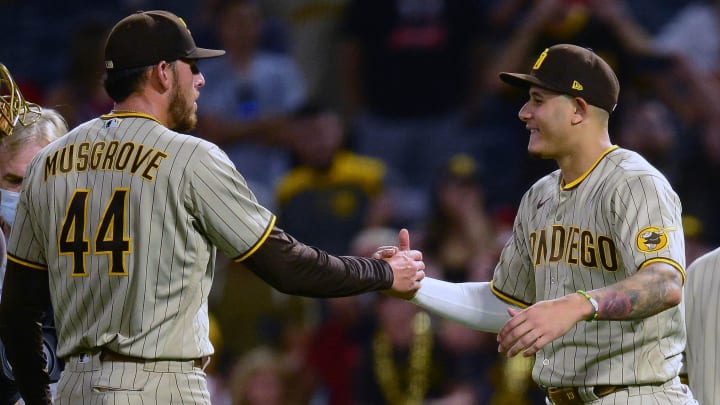 Aug 27, 2021; Anaheim, California, USA; San Diego Padres starting pitcher Joe Musgrove (44) and designated hitter Manny Machado (13) celebrate the 5-0 victory against the Los Angeles Angels at Angel Stadium. Mandatory Credit: Gary A. Vasquez-USA TODAY Sports