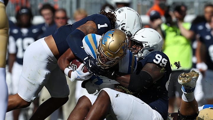 Oct 5, 2024; University Park, Pennsylvania, USA; Penn State Nittany Lions defensive tackle Coziah Izzard (99) and safety Jaylen Reed (1) stop UCLA Bruins running back Jalen Berger (0) during the third quarter at Beaver Stadium. Mandatory Credit: Matthew O'Haren-Imagn Images