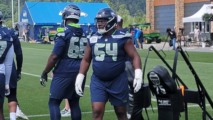 Seahawks rookie Christian Haynes listens to instructions from coach Scott Huff prior to a sled blocking drill at OTAs.