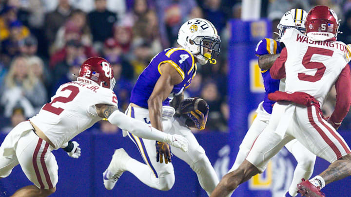 Nov 30, 2024; Baton Rouge, Louisiana, USA;  LSU Tigers wide receiver CJ Daniels (4) is chased after a catch by Oklahoma Sooners defensive back Billy Bowman Jr. (2) during the first quarter at Tiger Stadium. Mandatory Credit: Stephen Lew-Imagn Images