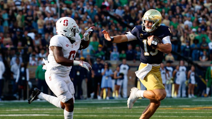 Notre Dame quarterback Riley Leonard (13) reaches out to stiff arm Stanford linebacker Gaethan Bernadel (0) during a NCAA college football game between Notre Dame and Stanford at Notre Dame Stadium on Saturday, Oct. 12, 2024, in South Bend.