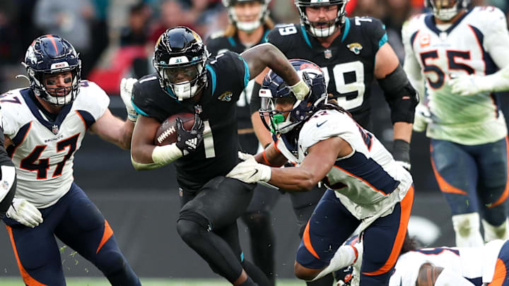 Oct 30, 2022; London, United Kingdom, Jacksonville Jaguars running back Travis Etienne Jr. (1) breaks a tackle from Denver Broncos linebacker Nik Bonitto (42) in the fourth quarter during an NFL International Series game at Wembley Stadium. Mandatory Credit: Nathan Ray Seebeck-Imagn Images