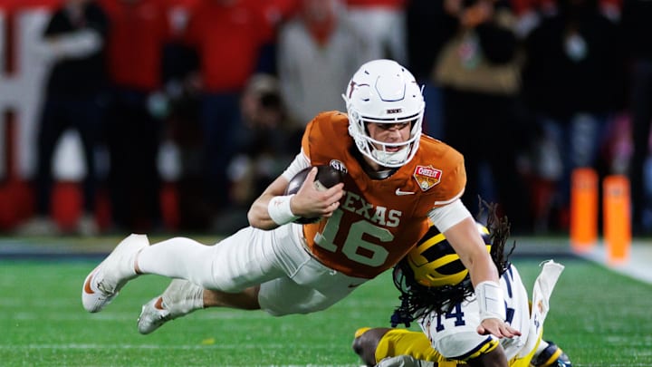 Dec 31, 2025; Orlando, FL, USA; Texas Longhorns quarterback Arch Manning (16) dives forward over Michigan Wolverines defensive back Jordan Young (14) during the second half at Camping World Stadium. Mandatory Credit: Matt Pendleton-Imagn Images