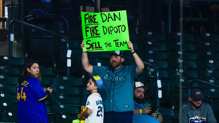 Sep 5, 2026; Seattle, Washington, USA; A Seattle Mariners fan holds a sign imploring the team to fire manager Dan Wilson (not pictured) and president of baseball operations Jerry Dipoto (not pictured) following a loss against the Athletics at T-Mobile Park. Mandatory Credit: Joe Nicholson-Imagn Images Sep 5, 2026; Seattle, Washington, USA; A Seattle Mariners fan holds a sign imploring the team to fire manager Dan Wilson (not pictured) and president of baseball operations Jerry Dipoto (not pictured) following a loss against the Athletics at T-Mobile Park. Mandatory Credit: Joe Nicholson-Imagn Images