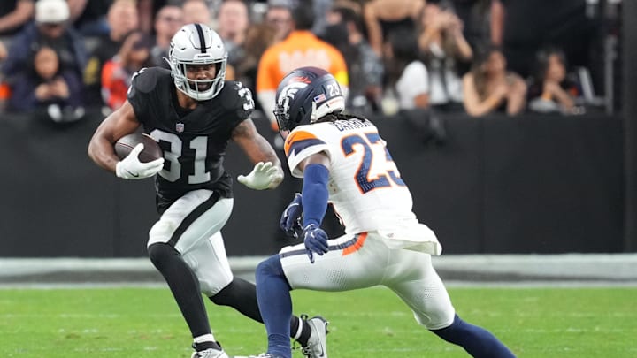 Dec 7, 2025; Paradise, Nevada, USA;  Las Vegas Raiders running back Raheem Mostert (31) carries the ball as Denver Broncos cornerback Jahdae Barron (23) defends during the second half at Allegiant Stadium. Mandatory Credit: Stephen R. Sylvanie-Imagn Images