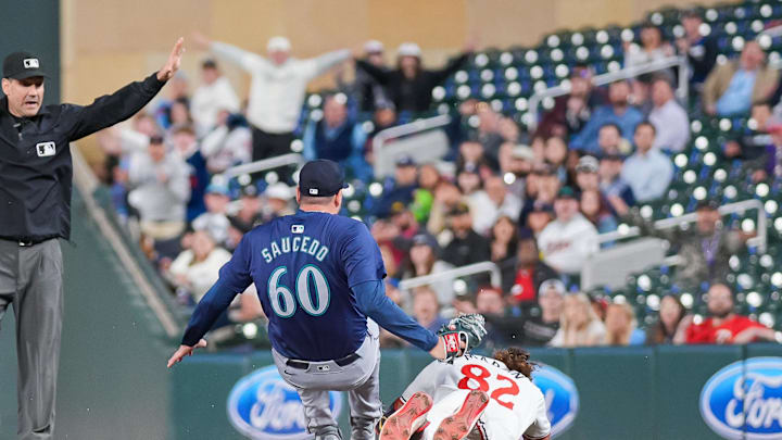 May 7, 2024; Minneapolis, Minnesota, USA; Minnesota Twins outfielder Austin Martin (82) slides into first against the Seattle Mariners pitcher Tayler Saucedo (60) in the eighth inning at Target Field. Mandatory Credit: Brad Rempel-USA TODAY Sports