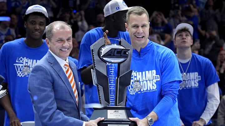 Mar 15, 2025; Charlotte, NC, USA; ACC commissioner Jim Phillips hands the championship trophy to Duke Blue Devils head coach Jon Scheyer after the 2025 ACC Conference Championship game against the Louisville Cardinals at Spectrum Center. Mandatory Credit: Jim Dedmon-Imagn Images