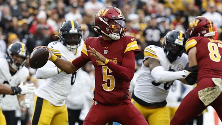 Washington Commanders quarterback Jayden Daniels passes the ball as Pittsburgh Steelers linebacker Patrick Queen defends.