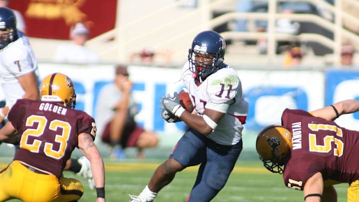 Nov 25, 2005; Tempe, AZ, USA; Arizona Wildcats running back Mike Bell (#11) slips past two Arizona State Sun Devils defenders Josh Golden (#23) and Beau Manutai (#51) at Sun Devil Stadium, Mandatory Credit: Rick Scuteri-Imagn Images Copyright Rick Scuteri Nov 25, 2005; Tempe, AZ, USA; Arizona Wildcats running back Mike Bell (#11) slips past two Arizona State Sun Devils defenders Josh Golden (#23) and Beau Manutai (#51) at Sun Devil Stadium, Mandatory Credit: Rick Scuteri-Imagn Images Copyright Rick Scuteri