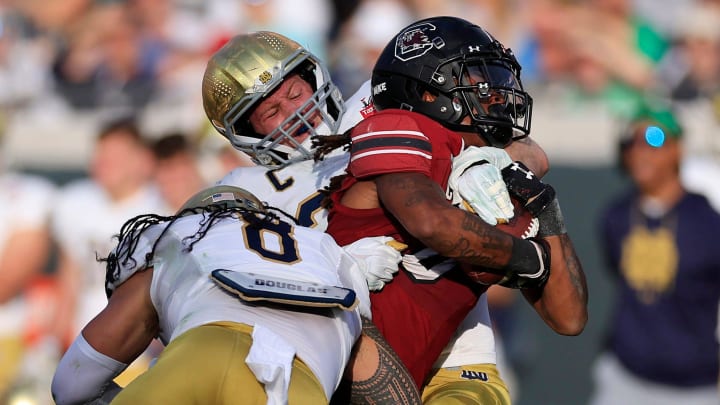 Notre Dame Fighting Irish linebacker JD Bertrand (27), center back, and linebacker Marist Liufau (8) tackle South Carolina Gamecocks running back Juju McDowell (0) during the first quarter of the TaxSlayer Gator Bowl of an NCAA college football game Friday, Dec. 30, 2022 at TIAA Bank Field in Jacksonville. The Notre Dame Fighting Irish held off the South Carolina Gamecocks 45-38.  