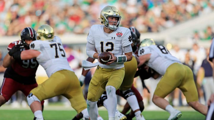 Notre Dame Fighting Irish quarterback Tyler Buchner (12) looks to handoff  during the first quarter of the TaxSlayer Gator Bowl of an NCAA college football game Friday, Dec. 30, 2022 at TIAA Bank Field in Jacksonville. The Notre Dame Fighting Irish held off the South Carolina Gamecocks 45-38. 