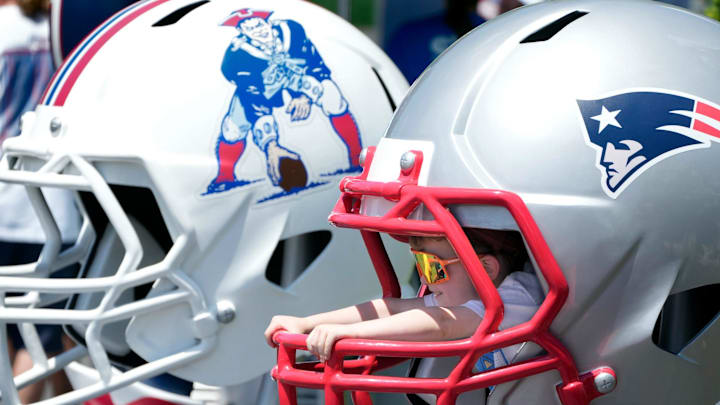 Hudson Ahern, of East Taunton, Massachusetts, poses for a photo inside one of two oversized Patriots helmets on opening day of the New England Patriots training camp July 23, 2025, at Gillette Stadium in Foxboro, Massachusetts.