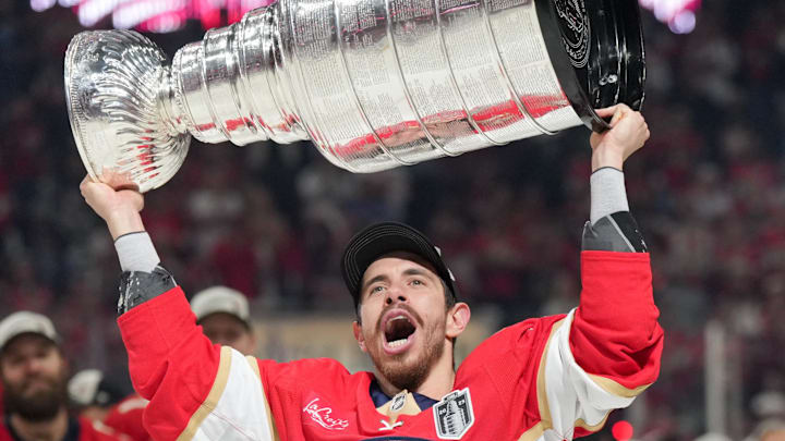 Jun 17, 2025; Sunrise, Florida, USA; Florida Panthers center Evan Rodrigues (17) hoists the Stanley Cup after winning game six of the 2025 Stanley Cup Final against the Edmonton Oilers at Amerant Bank Arena. Mandatory Credit: Jim Rassol-Imagn Images