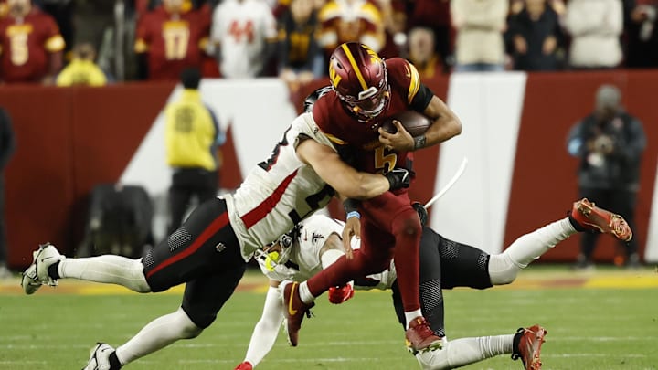 Washington Commanders quarterback Jayden Daniels is tackled by Atlanta Falcons linebacker Nate Landman.