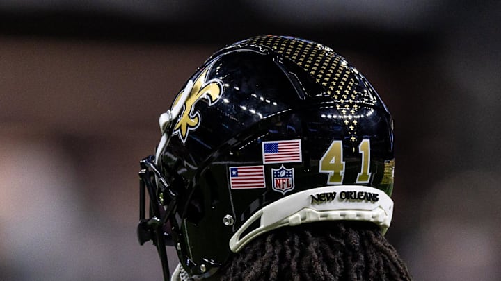 Sep 7, 2025; New Orleans, Louisiana, USA;  Detailed view of the helmet worn by New Orleans Saints running back Alvin Kamara (41) with and American Flag and the flag of Liberia during warmups against the Arizona Cardinals at Caesars Superdome. Mandatory Credit: Stephen Lew-Imagn Images