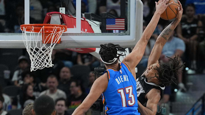 Mar 2, 2025; San Antonio, Texas, USA;  Oklahoma City Thunder forward Ousmane Dieng (13) blocks a shot by San Antonio Spurs guard Devin Vassell (24) in the second half at Frost Bank Center.