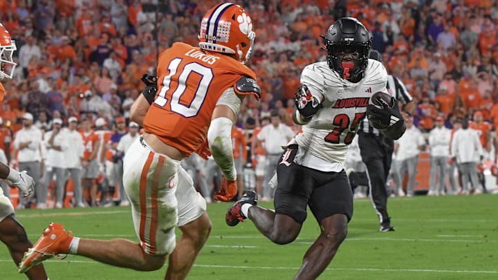 Nov 2, 2024; Clemson, South Carolina, USA; Louisville Cardinals running back Isaac Brown (25) runs the ball against Clemson Tigers cornerback Jeadyn Lukus (10) during the second quarter at Memorial Stadium.