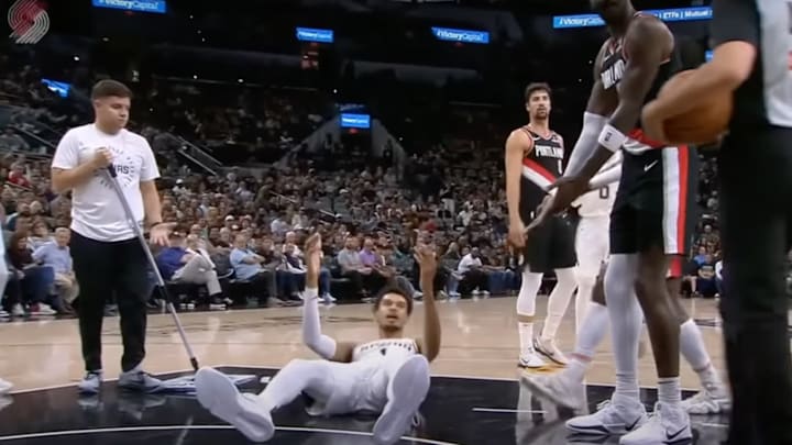 A mop boy wonders why Victor Wembanyama is on the floor during the Spurs - Blazers game.