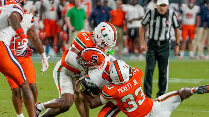 Nov 8, 2025; Miami Gardens, Florida, USA; Syracuse Orange quarterback Joseph Filardi (13) is sacked by Miami Hurricanes defensive back Dylan Day (23) and defensive lineman Booker Pickett (33) during the fourth quarter at Hard Rock Stadium. Mandatory Credit: Jeff Romance-Imagn Images