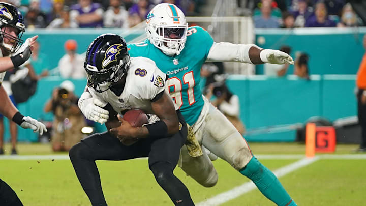 Nov 11, 2021; Miami Gardens, Florida, USA; Baltimore Ravens quarterback Lamar Jackson (8) breaks the sack attempt of Miami Dolphins defensive end Emmanuel Ogbah (91) during the second half at Hard Rock Stadium. Mandatory Credit: Jasen Vinlove-Imagn Images