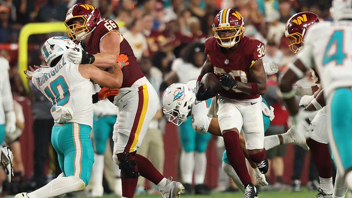Aug 14, 2026; Landover, Maryland, USA; Washington Commanders running back Robert Henry Jr. (30) carries the ball past Miami Dolphins linebacker Jacob Rodriguez (10), who is being manhandled by Matt Gulbin (66) during the first half at Northwest Stadium. Mandatory Credit: Geoff Burke-Imagn Images Aug 14, 2026; Landover, Maryland, USA; Washington Commanders running back Robert Henry Jr. (30) carries the ball past Miami Dolphins linebacker Jacob Rodriguez (10), who is being manhandled by Matt Gulbin (66) during the first half at Northwest Stadium. Mandatory Credit: Geoff Burke-Imagn Images