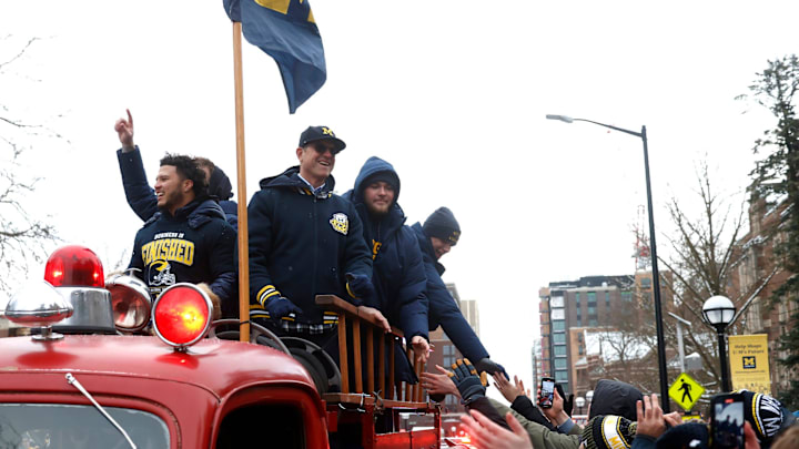 Michigan fans rush an old fire truck to shake hands with Michigan head football coach Jim Harbaugh