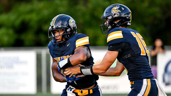 Haslett's Kory Amachree, left, takes a handoff form quarterback Erik Lardie during the first quarter in the game against DeWitt on Thursday, Aug. 29, 2024, at Haslett High School.
