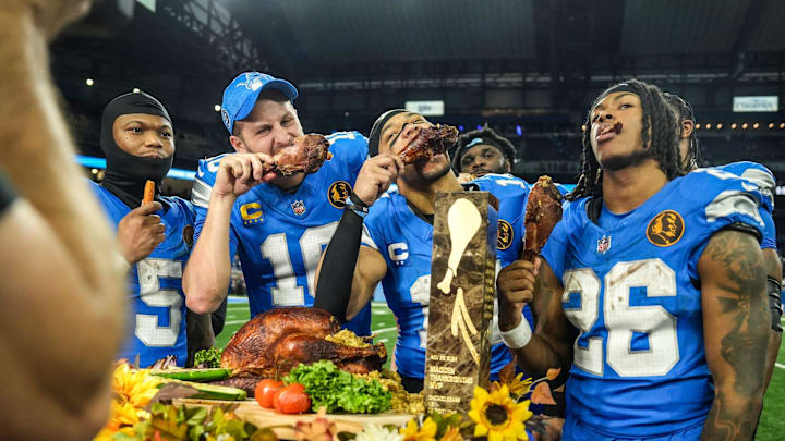 Detroit Lions quarterback Jared Goff (16), defensive tackle DJ Reader (98), wide receiver Amon-Ra St. Brown (14), running back Jahmyr Gibbs (26), linebacker Al-Quadin Muhammad (69) celebrate their win against the Chicago Bears with a turkey drumstick after winning 23-20 on Thanksgiving Day at Ford Field in Detroit on Thursday, Nov. 28, 2024.
