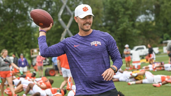 Clemson offensive coordinator Garrett Riley throws a ball as players warm up during preseason practice in Jervey Meadows in Clemson, S.C. Thursday, August 10, 2023.