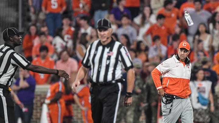 Nov 2, 2024; Clemson, South Carolina, USA; A referee tosses a water bottle to the sideline near Clemson Tigers head coach Dabo Swinney after people in the stands threw bottles on the field after a call in favor of the Louisville Cardinals during the fourth quarter at Memorial Stadium. Mandatory Credit: Ken Ruinard-Imagn Images
