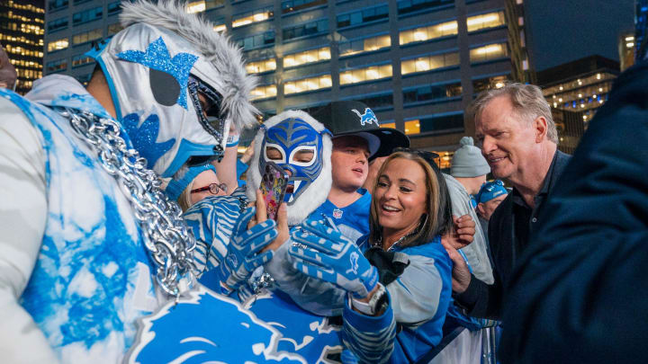 Detroit Lions fans Christopher Guiao, 47, of Sterling Heights, left in mask, and Reiner Calderero, 41, of Warren in mask, try to get a photo with NFL commissioner Roger Goodell on Friday, April 26, 2024 for the second day of the NFL draft in Detroit.
