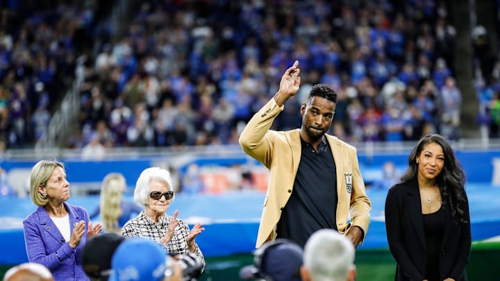 Calvin Johnson waves to Detroit Lions fans as Sheila Ford Hamp, far left, and Martha Firestone Ford, left, clap during Johnson's Hall of Fame Ring Ceremony at Ford Field in Detroit on Sunday, Sept. 26, 2021. At right is Johnson's wife, Brittney.