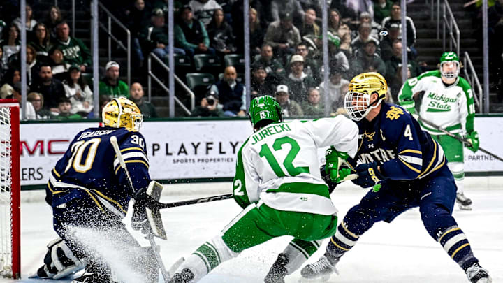 Michigan State's Griffin Jurecki, center, stops in front of the goal between Notre Dame's Luke Pearson, left, and Michael Mastrodomenico, right, while the Spartans attempt to score during the third period on Thursday, Feb. 19, 2026, at the Munn Ice Arena in East Lansing. Michigan State's Griffin Jurecki, center, stops in front of the goal between Notre Dame's Luke Pearson, left, and Michael Mastrodomenico, right, while the Spartans attempt to score during the third period on Thursday, Feb. 19, 2026, at the Munn Ice Arena in East Lansing.