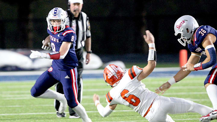 Bedford North Lawrence's Brody Horton (8) rushes for yardage as he runs past Columbus East defender Brody Miller (6) on Friday, Oct. 18, 2024.