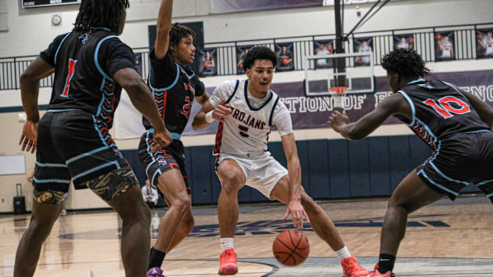 East Lansing's Cameron Hutson (5) is surrounded by Everett players from left, Javari Funches (1) Malcolm Pulley (22) and Kharon Tunley (10) in prep basketball Friday, Jan. 31, 2025.