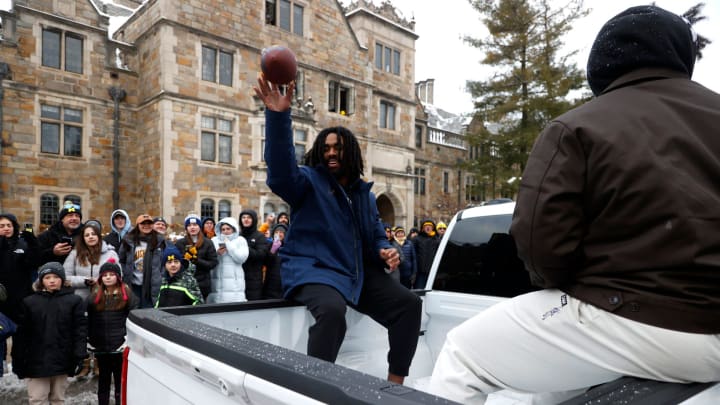 Michigan running back Donovan Edwards throws a football back to a young fan during a parade for the