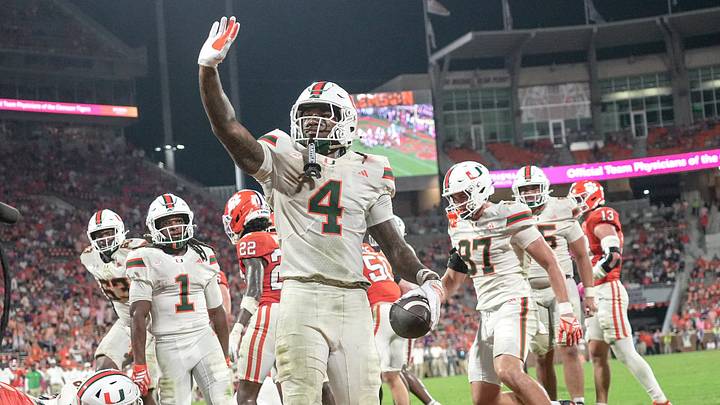 Miami Hurricanes running back Mark Fletcher Jr. (4) dives over the top of Clemson players for a touchdown and lands on his feet and waves to fans during the fourth quarter at Memorial Stadium Saturday, October 3, 2026. Miami Hurricanes running back Mark Fletcher Jr. (4) dives over the top of Clemson players for a touchdown and lands on his feet and waves to fans during the fourth quarter at Memorial Stadium Saturday, October 3, 2026.