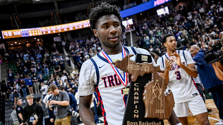 East Lansing's KJ Torbert carries the championship trophy after beating Wayne Memorial to win the Division 1 state title on Saturday, March 15, 2025, at the Breslin Center in East Lansing.
