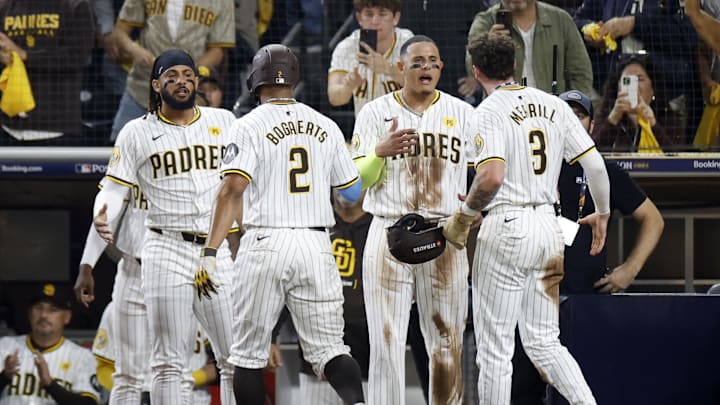 Oct 8, 2024; San Diego, California, USA; San Diego Padres second baseman Xander Bogaerts (2) and outfielder Jackson Merrill (3) celebrate with outfielder Fernando Tatis Jr. (23), left, and third baseman Manny Machado (13) after scoring in the second inning against the Los Angeles Dodgers during game three of the NLDS for the 2024 MLB Playoffs at Petco Park. Mandatory Credit: David Frerker-Imagn Images