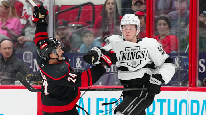 Feb 1, 2025; Raleigh, North Carolina, USA;  Los Angeles Kings defenseman Brandt Clarke (92) checks Carolina Hurricanes center Seth Jarvis (24) during the third period at Lenovo Center. Mandatory Credit: James Guillory-Imagn Images