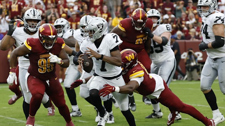 Sep 21, 2025; Landover, Maryland, USA; Las Vegas Raiders quarterback Geno Smith (7) is tackled by Washington Commanders defensive end Javontae Jean-Baptiste (90) during the third quarter at Northwest Stadium. Mandatory Credit: Geoff Burke-Imagn Images