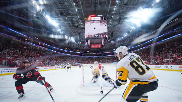 Jan 5, 2025; Raleigh, North Carolina, USA;  Pittsburgh Penguins center Sidney Crosby (87) clears the puck away from Carolina Hurricanes center Jack Roslovic (96) during the third period at Lenovo Center. Mandatory Credit: James Guillory-Imagn Images